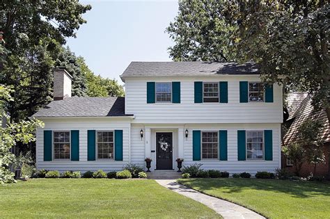 white house with black shutters and metal roof|white brick house black shutters.